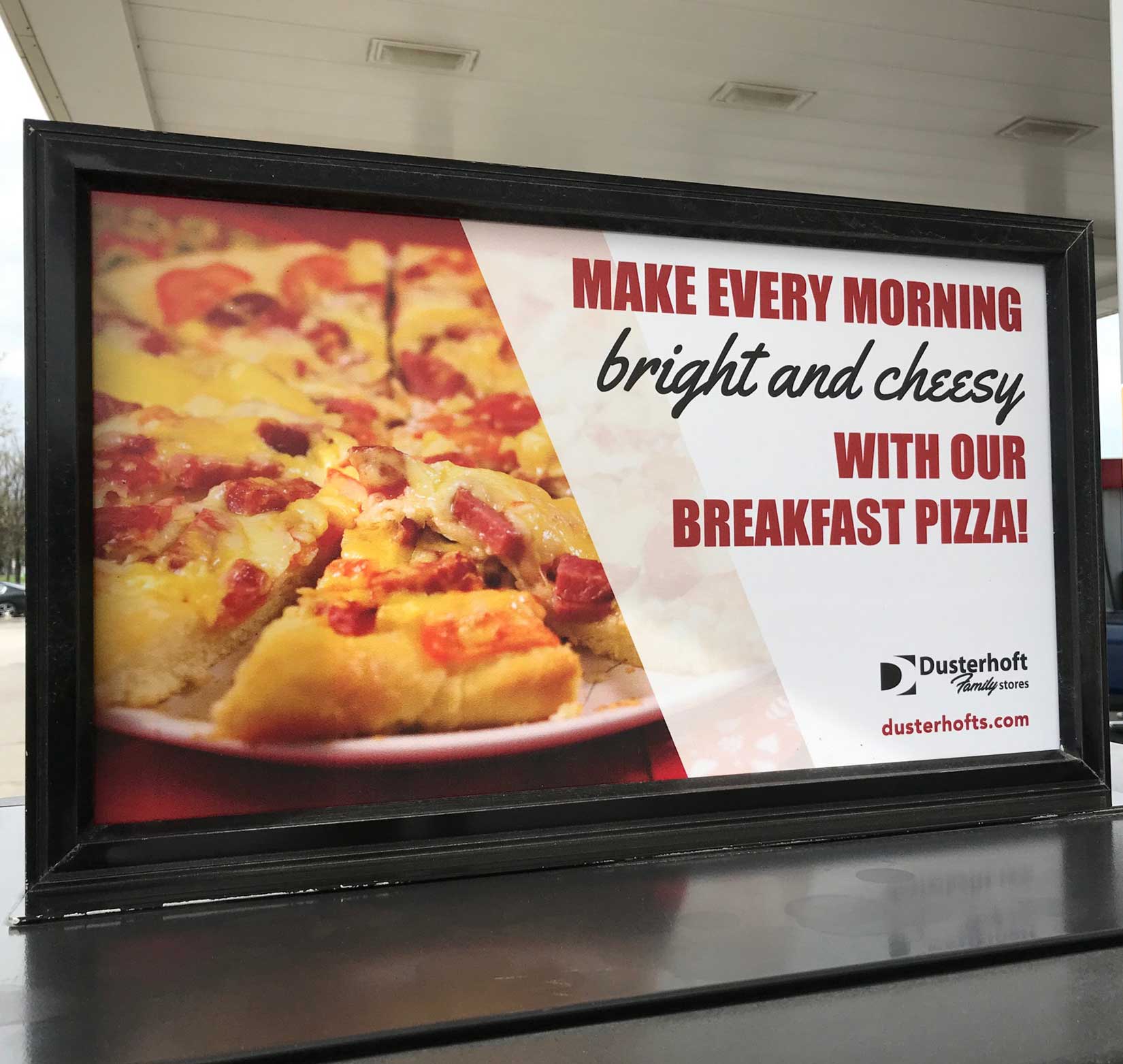 A printed poster advertising breakfast pizza inside Dusterhoft Family Stores