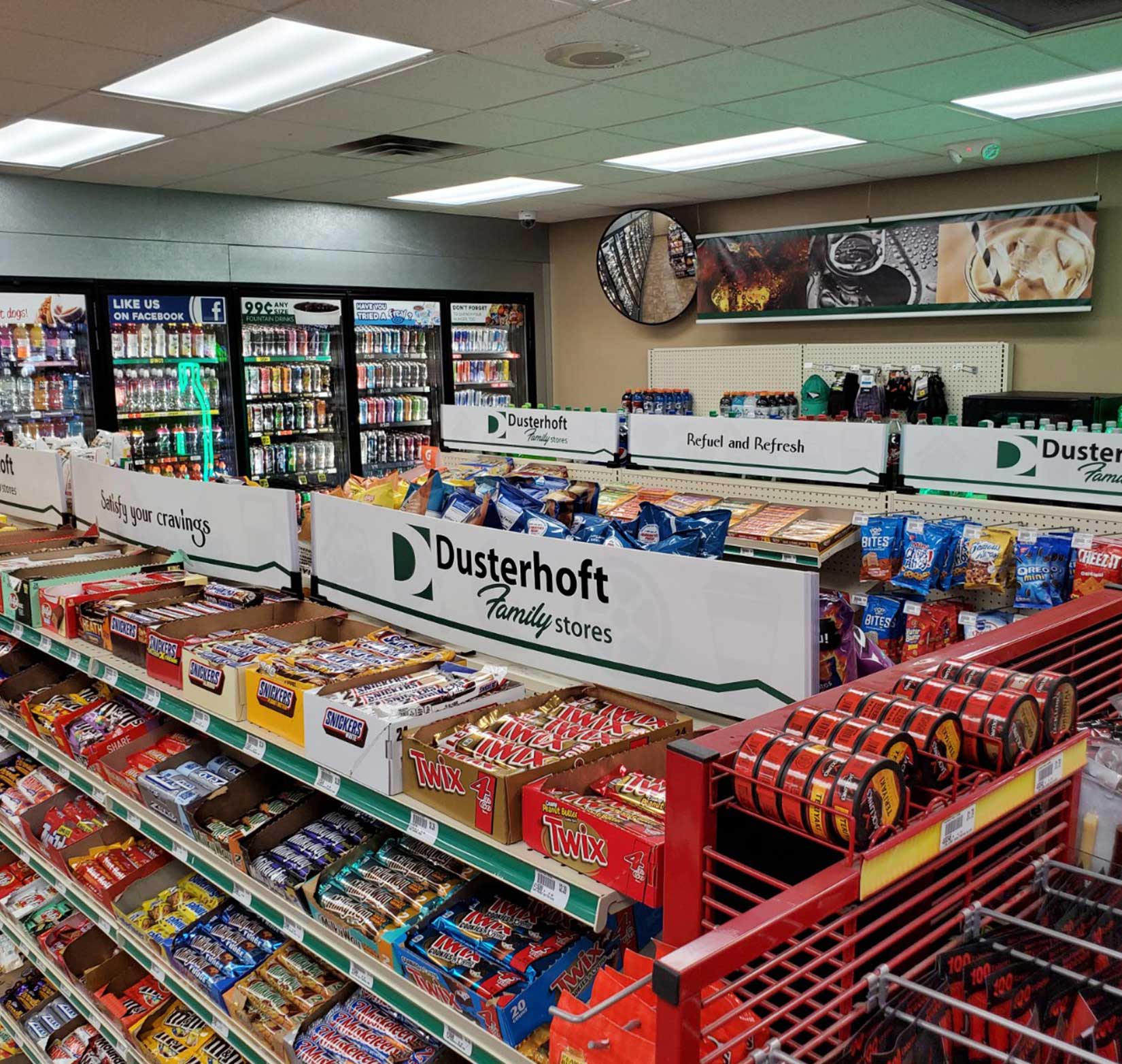 A row of white signs with the Dusterhoft Family Stores logo above the candy and snack section of the company’s C-store
