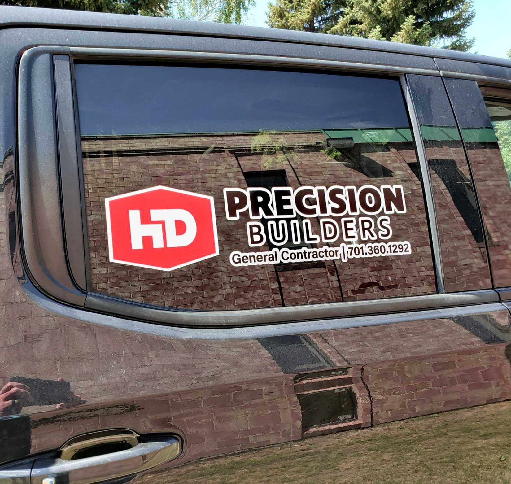 A vinyl decal for Precision Builders on the side window of a black truck